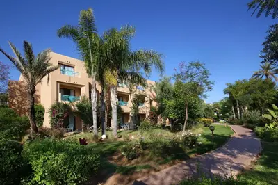 an apartment building with palm trees and a driveway at Valeria Madina Club - All Inclusive in Marrakech