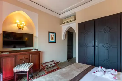 a bedroom with a bed and a dresser and a tv at Le Caspien Boutique Hotel in Marrakech