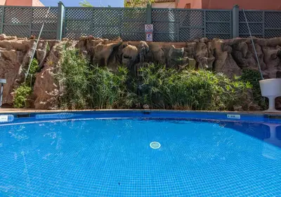 a large blue swimming pool in front of a rock wall at Le Caspien Boutique Hotel in Marrakech