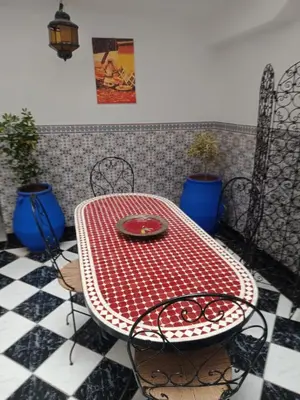 a red table and chairs on a checkered floor at Riad NEJJARINE in Marrakech