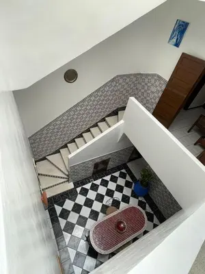 a view of a staircase with a table and a checkerboard floor at Riad NEJJARINE in Marrakech