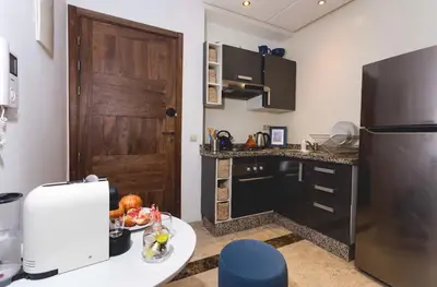 a kitchen with a refrigerator and a table with a plate of food at Stylish Studio(WiFi, Netflix, Pool, AC, Nespresso) in Marrakech