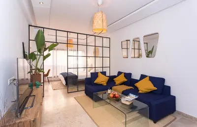 a living room with a blue couch and yellow pillows at Stylish Studio(WiFi, Netflix, Pool, AC, Nespresso) in Marrakech