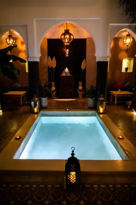 a large swimming pool in a room with lights at Riad Alnadine in Marrakech