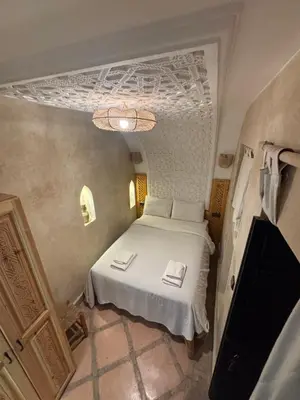a small bedroom with a white bed with towels on it at Riad Minami in Marrakech
