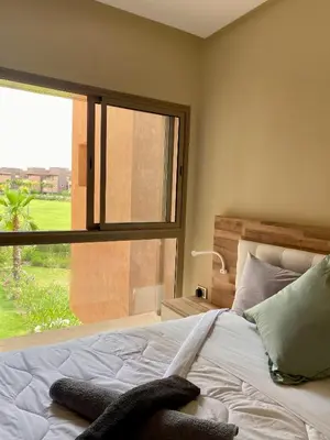 a bedroom with a bed and a large window at Comme a la maison Prestigia Golf acces piscine in Marrakech