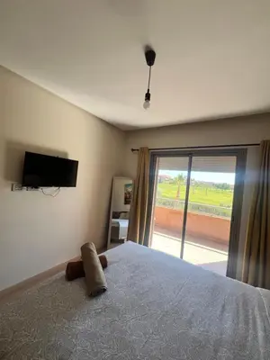 a bedroom with a bed with a television and a window at Comme a la maison Prestigia Golf acces piscine in Marrakech