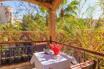 a table with red umbrellas sitting on a balcony at Villa avec piscine - Petit déjeuner Gratuit - Marrakech City Center in Marrakech