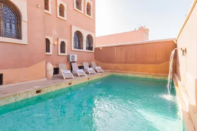 a swimming pool with chairs in a building at Villa avec piscine - Petit déjeuner Gratuit - Marrakech City Center in Marrakech