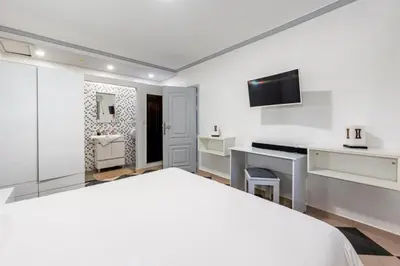 a white bedroom with a large bed and a bathroom at Villa avec piscine - Petit déjeuner Gratuit - Marrakech City Center in Marrakech