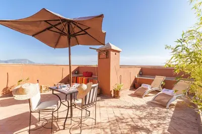 a patio with a table and chairs and an umbrella at Villa avec piscine - Petit déjeuner Gratuit - Marrakech City Center in Marrakech