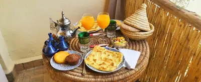 a rattan table with food and drinks and orange juice at Riad Ayada in Marrakech