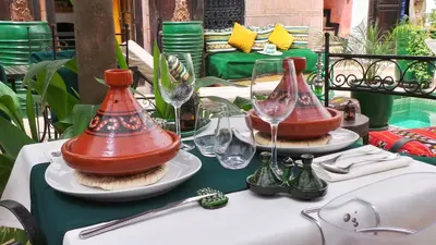 a table with two wine glasses on top of it at Riad Ayada in Marrakech