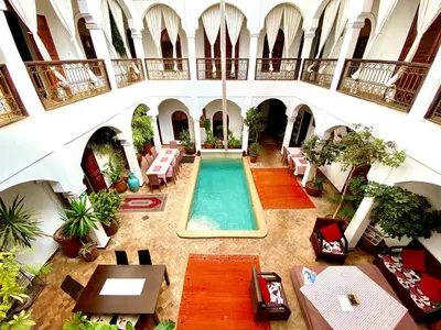 an indoor pool in a building with tables and chairs at Riad Mandalay in Marrakech