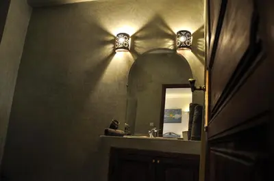 a bathroom with a mirror and lights on the wall at Riad Mandalay in Marrakech