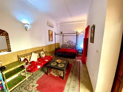 a living room with a red couch and a bed at Riad Mandalay in Marrakech