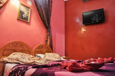 a bedroom with two beds and a tv on a wall at Riad Fattouma Kasba in Marrakech