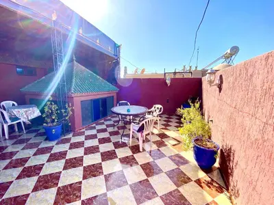 a patio with a table and chairs on a checkered floor at Riad Fattouma Kasba in Marrakech