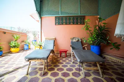 two chairs and a table on a patio with plants at Riad Inaka in Marrakech