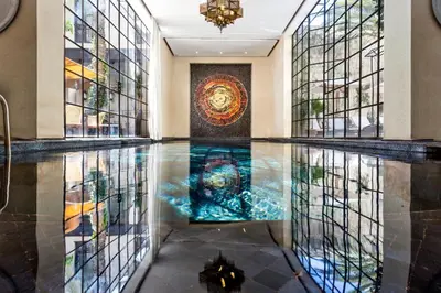 a pool in a hotel lobby with a painting on the wall at Palais Khum in Marrakech