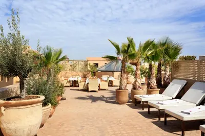 a patio with tables and trees and palm trees at Palais Khum in Marrakech