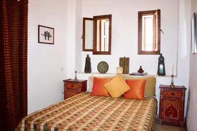 a bedroom with a bed with orange and yellow pillows at Riad Ben Youssef in Marrakech