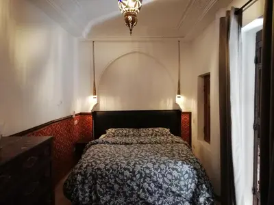 a bedroom with a bed and a chandelier at Riad Ben Youssef in Marrakech