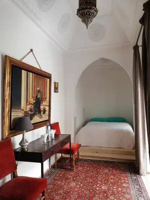 a bedroom with a bed and a table and a chair at Riad Ben Youssef in Marrakech