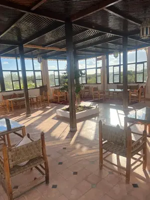 a large room with tables and benches and windows at Oloft in Marrakech