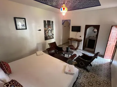 a room with a bed and a living room with chairs at Oloft in Marrakech