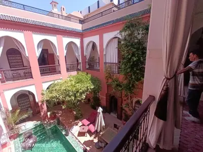 a man standing on a balcony of a building with a pool at Riad Zagouda in Marrakech