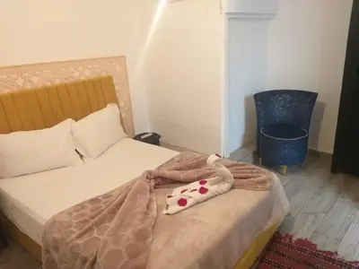 a bedroom with a bed with a blanket and a chair at Hôtel Agnaou in Marrakech