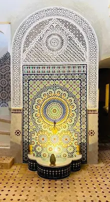 a mosaic tile wall with a fountain in a room at house miss rose in Marrakech