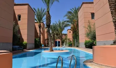 a swimming pool with palm trees in a resort at Riads Dar ZAO - logements entiers in Marrakech