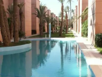 a swimming pool in front of a building with palm trees at Riads Dar ZAO - logements entiers in Marrakech