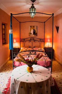 a bedroom with a bed with a black frame and a table at Riad zen&zin in Marrakech
