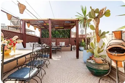 a patio with a table and chairs and a plant at Riad zen&zin in Marrakech
