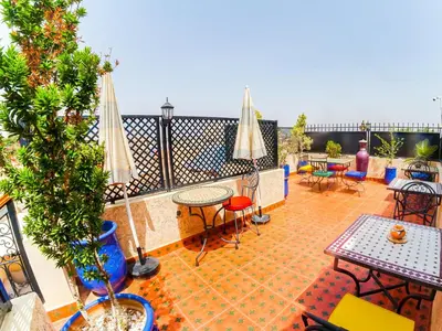 an outdoor patio with tables and chairs and umbrellas at Riad Dar Yassine in Marrakech