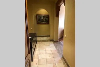 a hallway with a tile floor and a painting on the wall at Bel appartement au Rez-de-jardin dans la palmeraie in Marrakech
