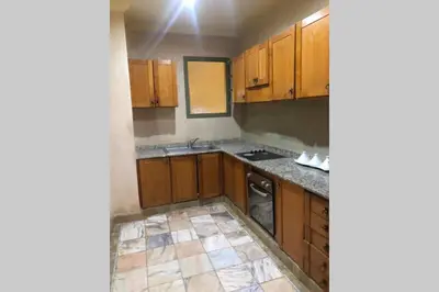a kitchen with wooden cabinets and a tile floor at Bel appartement au Rez-de-jardin dans la palmeraie in Marrakech
