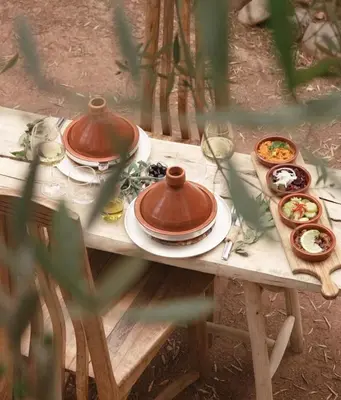 a wooden table with plates and bowls of food on it at Jnan Lotf Marrakech - Le Jardin de la Bienveillance in Marrakech