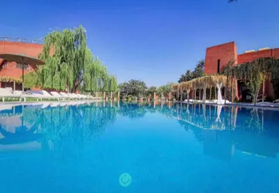 a large pool of blue water in front of a building at Jnan Lotf Marrakech - Le Jardin de la Bienveillance in Marrakech