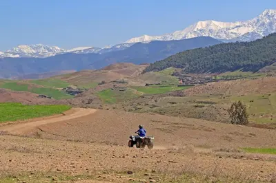 a person riding a wheeler in a field with mountains at Villa Selma avec piscine chauffée in Marrakech