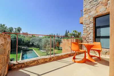 a balcony with orange chairs and a table and a pool at Villa ZITOUNA in Marrakech