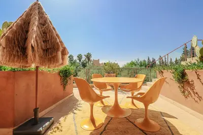 a patio with a table and chairs and a umbrella at Villa ZITOUNA in Marrakech
