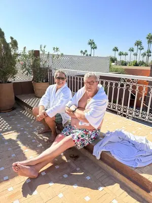 two older men sitting on a bench on a balcony at 