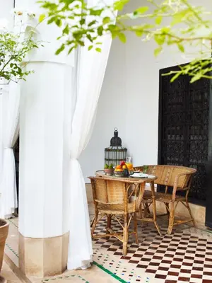a table and chairs in a room with white curtains at Riad L'Hôtel Marrakech in Marrakech