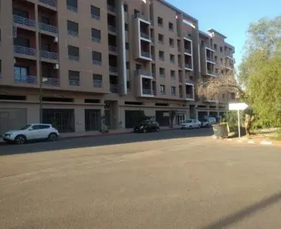 an empty street in front of a large apartment building at Superbe appartement Hivernage in Marrakech