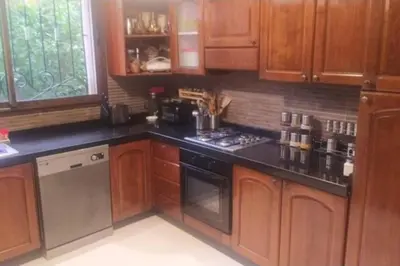 a kitchen with wooden cabinets and black counter tops at Magnifique villa avec piscine chauffée que pour famille in Marrakech