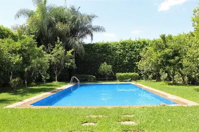 a swimming pool in a yard with grass and trees at Magnifique villa avec piscine chauffée que pour famille in Marrakech
